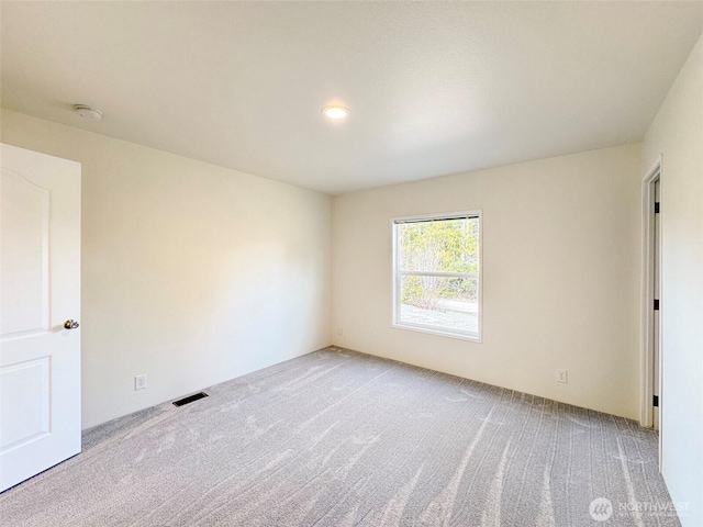 empty room featuring visible vents and light carpet