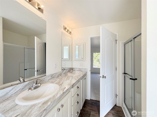 full bath with a shower stall, wood finished floors, double vanity, and a sink