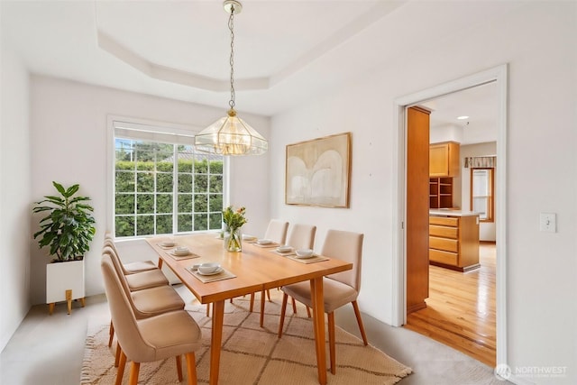 dining area featuring light wood-type flooring, a tray ceiling, and a chandelier