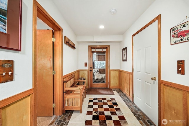 doorway to outside featuring recessed lighting, a wainscoted wall, and wood walls