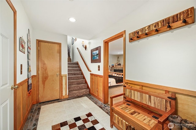 foyer entrance with stairs, wooden walls, recessed lighting, and wainscoting