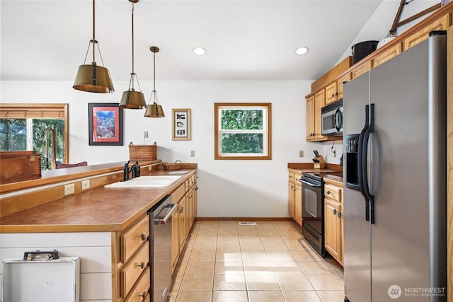 kitchen featuring a sink, appliances with stainless steel finishes, a peninsula, light tile patterned floors, and baseboards