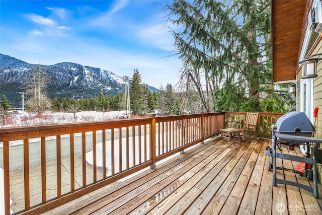 snow covered deck with a mountain view and grilling area