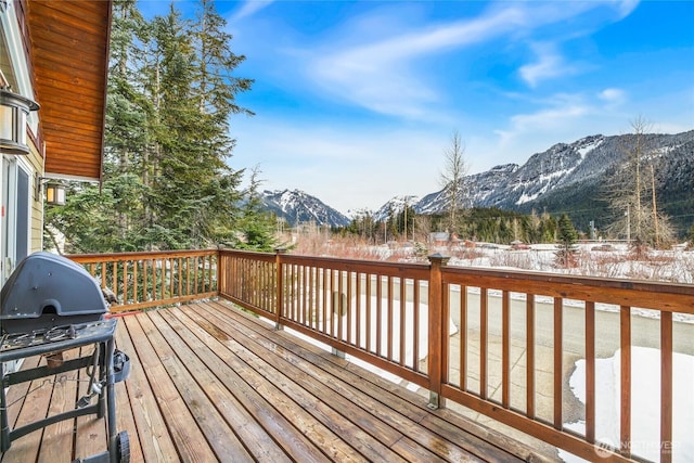 snow covered deck with a grill and a mountain view