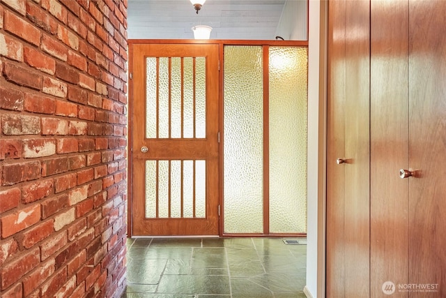 entryway featuring visible vents and brick wall