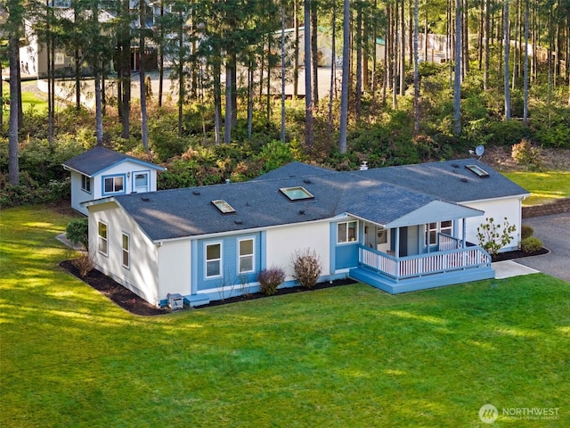 back of house with covered porch, a lawn, an outdoor structure, and roof with shingles