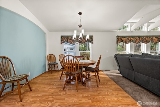 dining area featuring light wood finished floors, a chandelier, and lofted ceiling