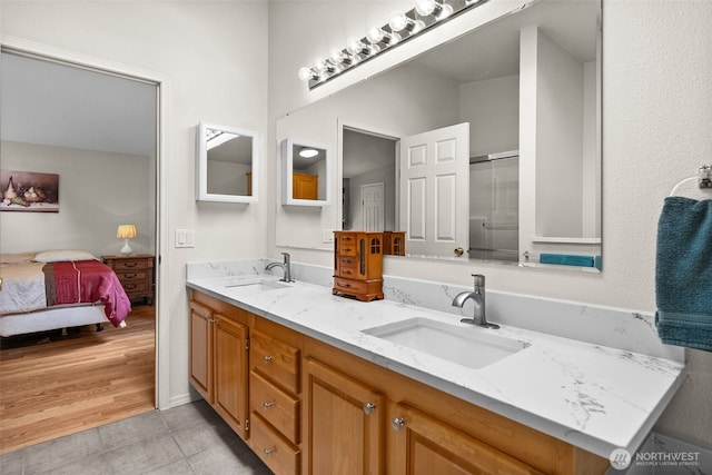 ensuite bathroom featuring tile patterned floors, a shower with door, double vanity, and a sink