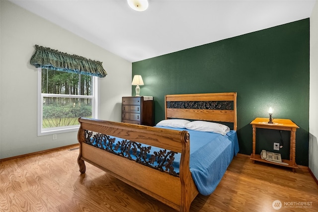 bedroom with lofted ceiling and wood finished floors