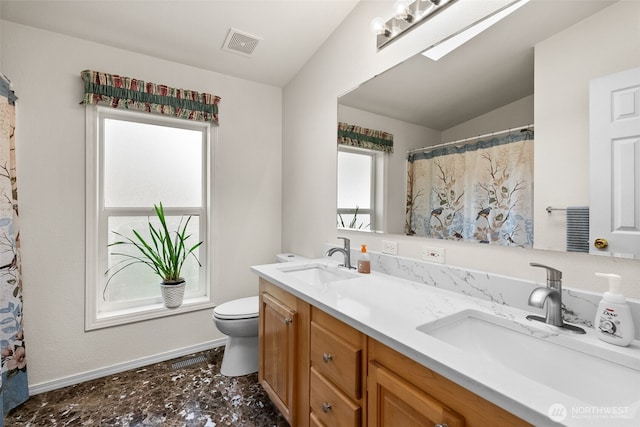 bathroom with a sink, visible vents, toilet, and double vanity