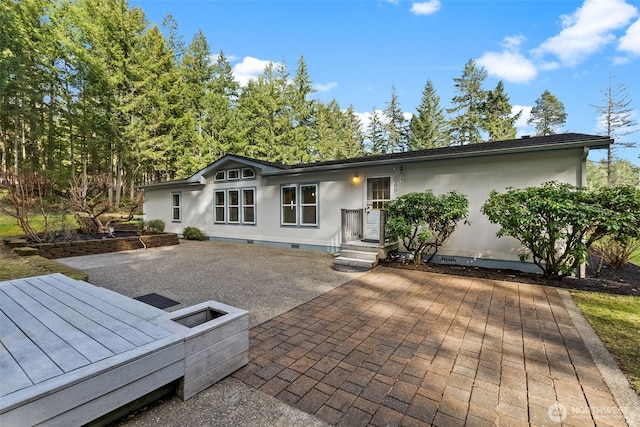 rear view of property with a patio, stucco siding, and crawl space