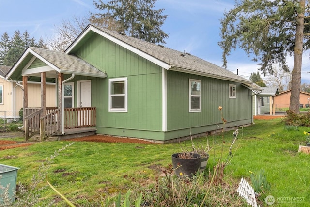 back of property featuring a yard and a shingled roof