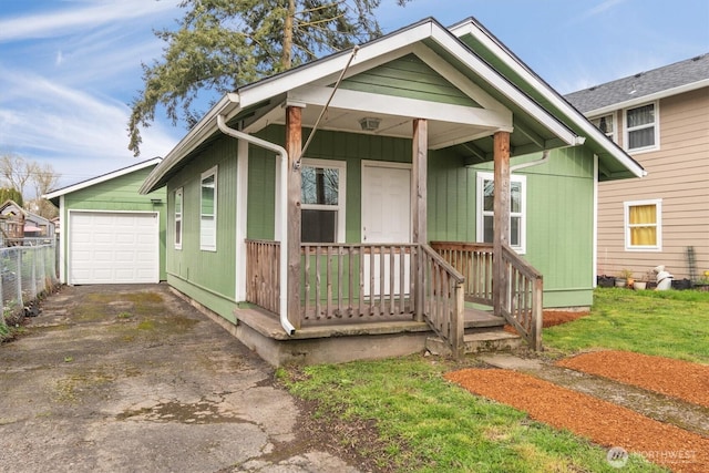 view of front of house with aphalt driveway, fence, covered porch, an outdoor structure, and an attached garage