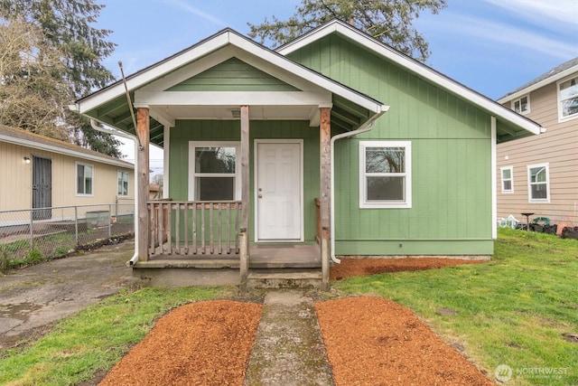 view of front of property featuring covered porch, a front lawn, and fence