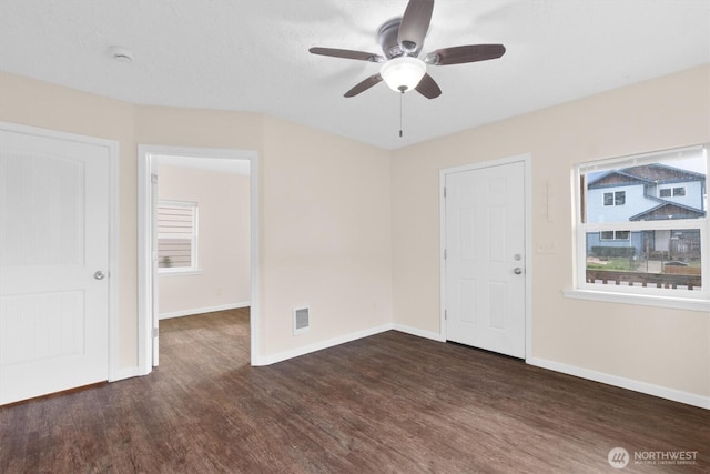 spare room featuring ceiling fan, visible vents, baseboards, and wood finished floors