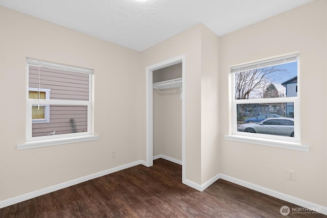 unfurnished bedroom featuring dark wood-style floors, baseboards, and a closet