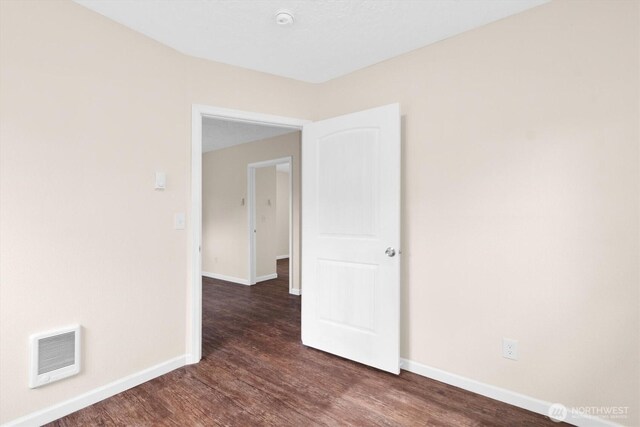 empty room featuring visible vents, baseboards, and wood finished floors