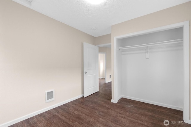 unfurnished bedroom with visible vents, baseboards, and dark wood-style flooring