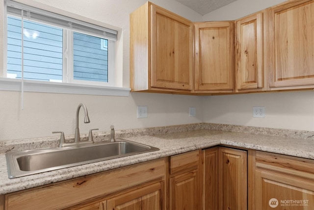 kitchen with light brown cabinetry, light countertops, and a sink