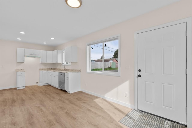 kitchen featuring baseboards, under cabinet range hood, dishwasher, light wood-type flooring, and a sink