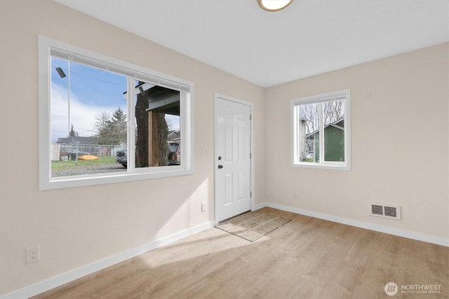 spare room featuring visible vents, baseboards, and wood finished floors