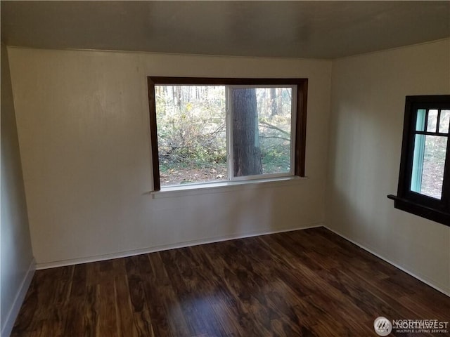 empty room featuring baseboards and dark wood-type flooring