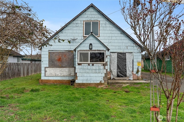 back of house featuring a lawn, an outdoor structure, and fence