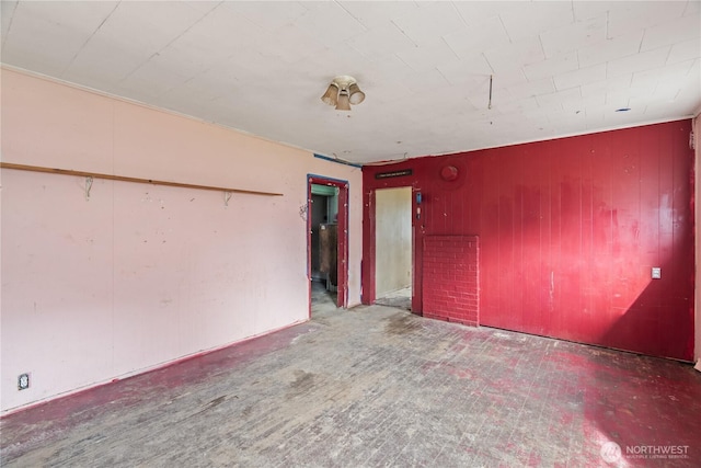 unfurnished room featuring wood walls