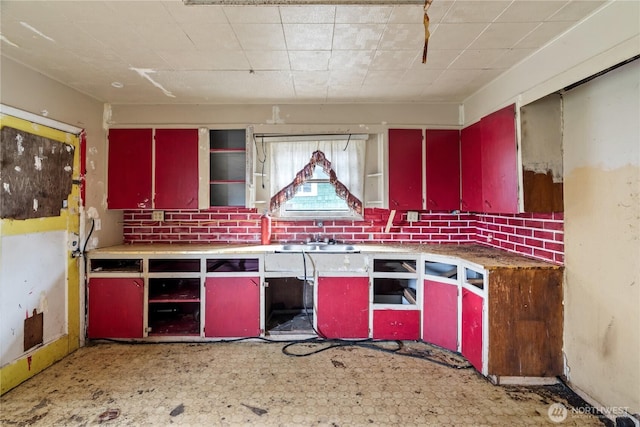 kitchen with red cabinetry, a sink, tile patterned floors, and yellow cabinets