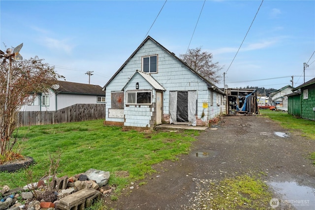 rear view of property with an outbuilding, fence, and a lawn