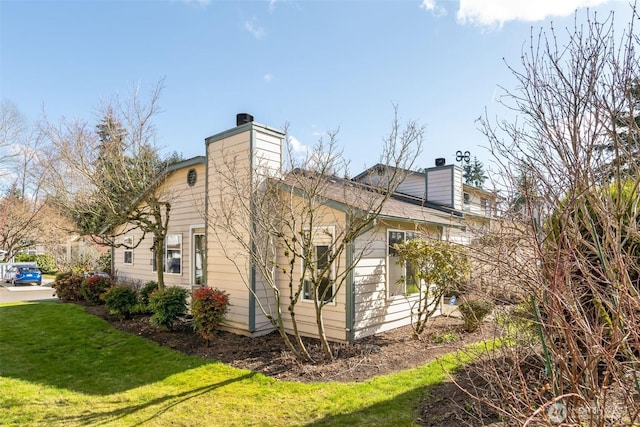 view of side of home with a yard and a chimney