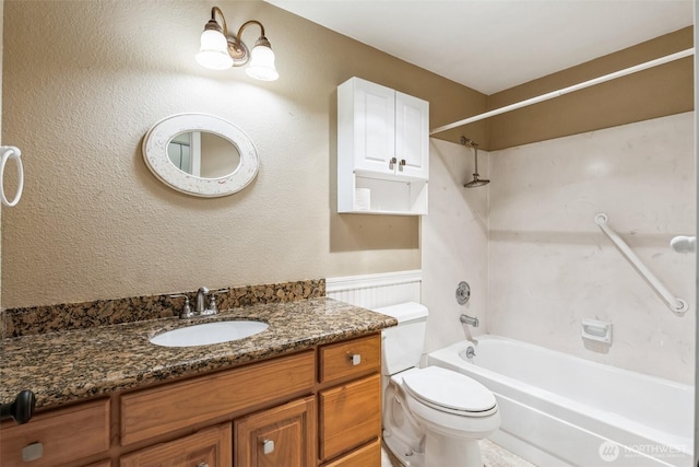 bathroom with a wainscoted wall, shower / tub combination, vanity, and toilet