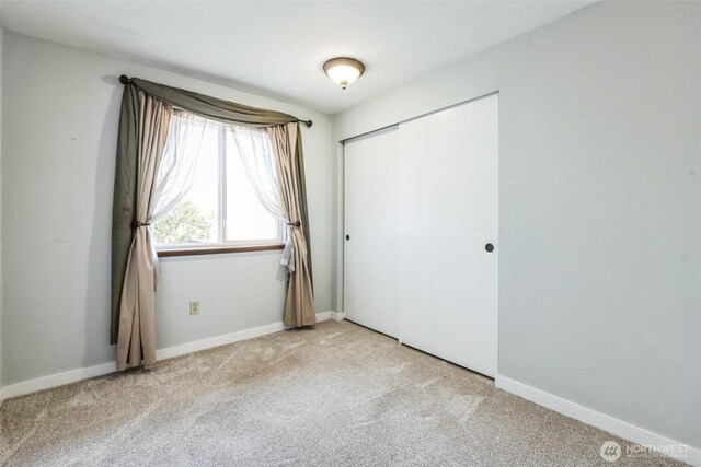 unfurnished bedroom featuring carpet, a closet, and baseboards