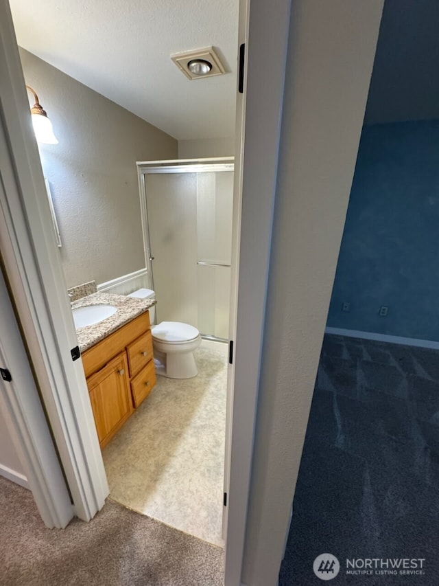 bathroom featuring toilet, a stall shower, and vanity