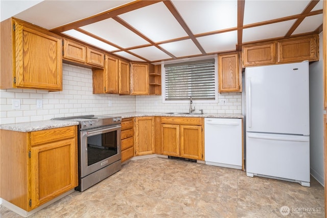 kitchen featuring light stone countertops, decorative backsplash, brown cabinetry, white appliances, and a sink