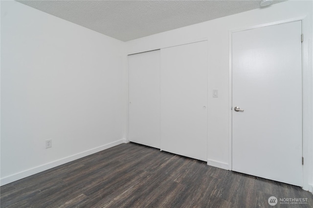 unfurnished bedroom with baseboards, dark wood-style flooring, a closet, and a textured ceiling