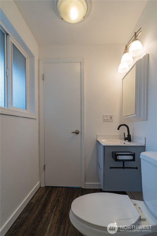 bathroom featuring vanity, toilet, wood finished floors, and baseboards