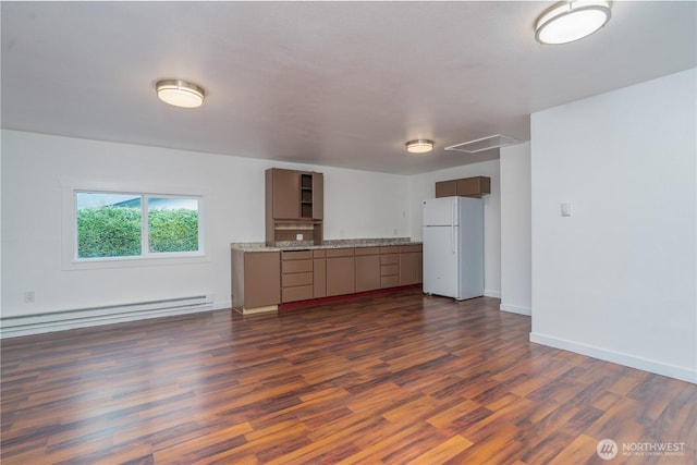 kitchen with a baseboard heating unit, baseboards, dark wood-style flooring, and freestanding refrigerator