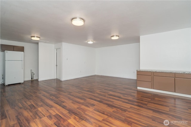 empty room with dark wood-type flooring and baseboards