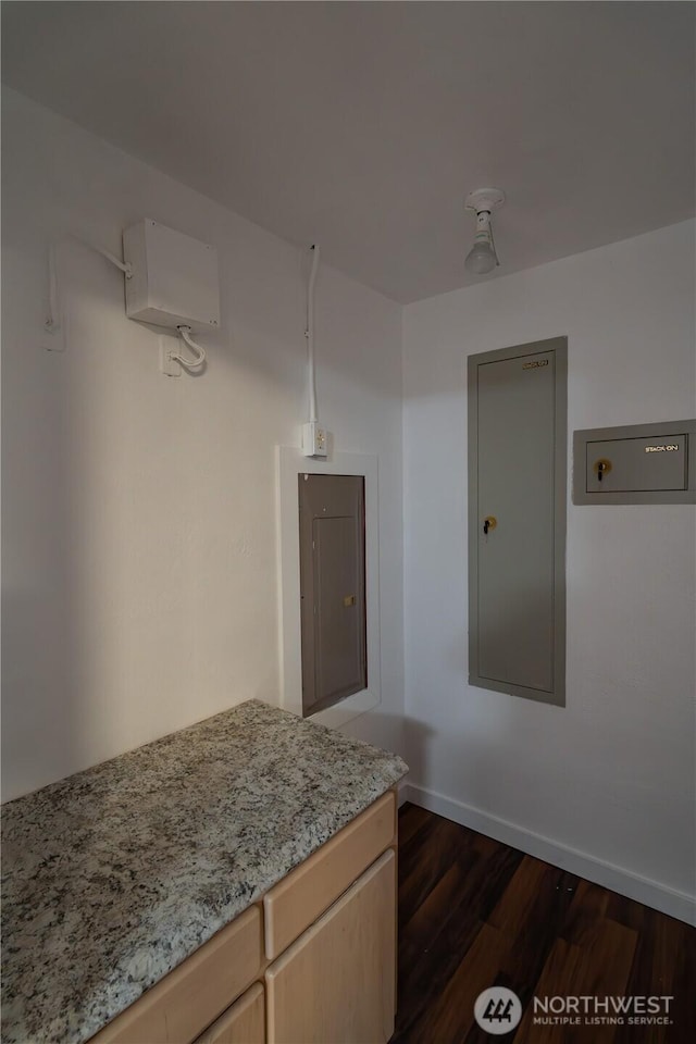 kitchen with dark wood finished floors, light brown cabinetry, baseboards, and light stone countertops