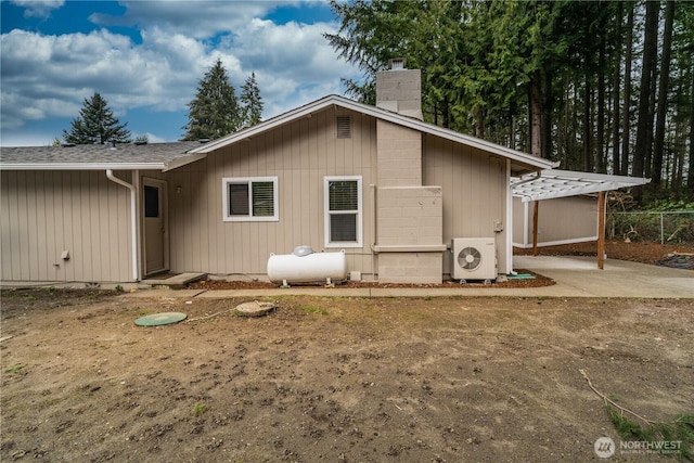 back of property with a shingled roof, ac unit, fence, and a chimney