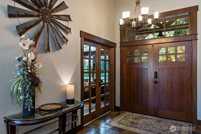 foyer entrance featuring a notable chandelier, stone finish floor, and french doors