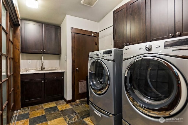 laundry area featuring washing machine and dryer, cabinet space, visible vents, and a sink