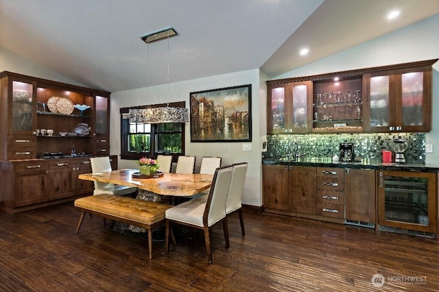 dining room featuring dark wood-style floors, a bar, beverage cooler, and vaulted ceiling