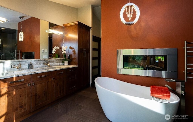 full bath featuring tile patterned floors, vanity, and a freestanding tub