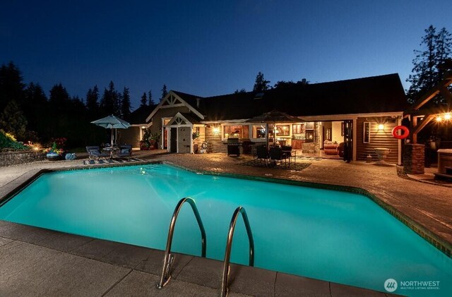 pool at twilight featuring outdoor dining space, a patio, and an outdoor pool