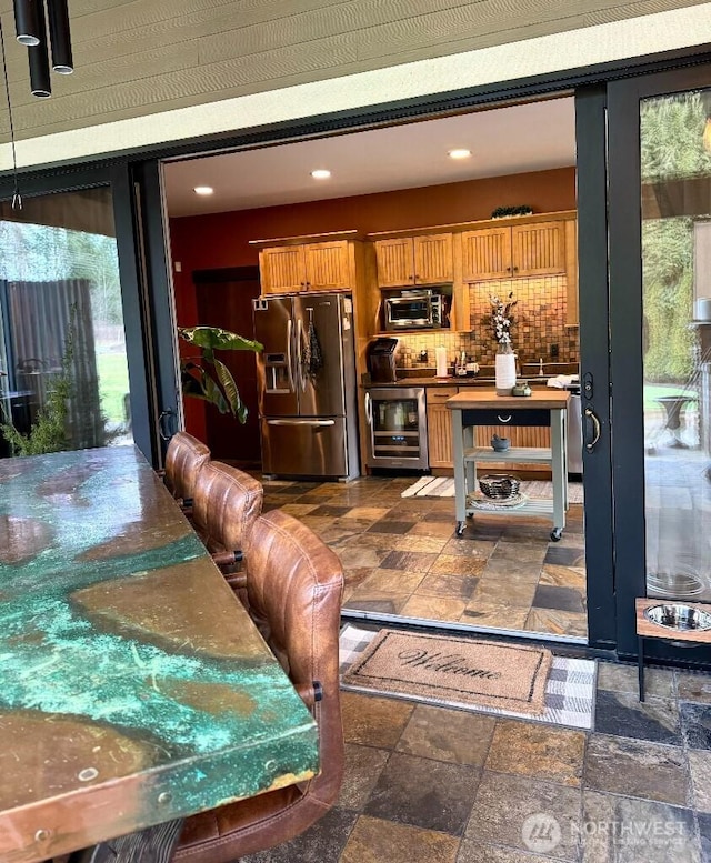 bar featuring stone tile floors, beverage cooler, recessed lighting, decorative backsplash, and appliances with stainless steel finishes