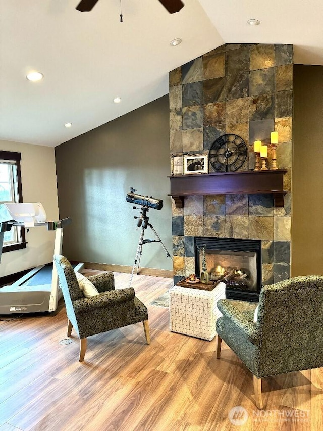 sitting room featuring vaulted ceiling, a fireplace, a ceiling fan, and wood finished floors