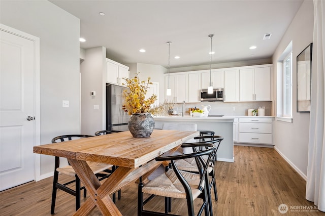 dining room featuring light wood-type flooring, visible vents, baseboards, and recessed lighting