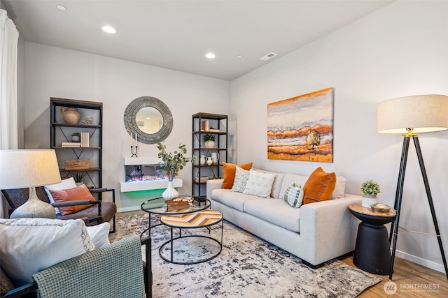 living area with recessed lighting, wood finished floors, visible vents, and baseboards